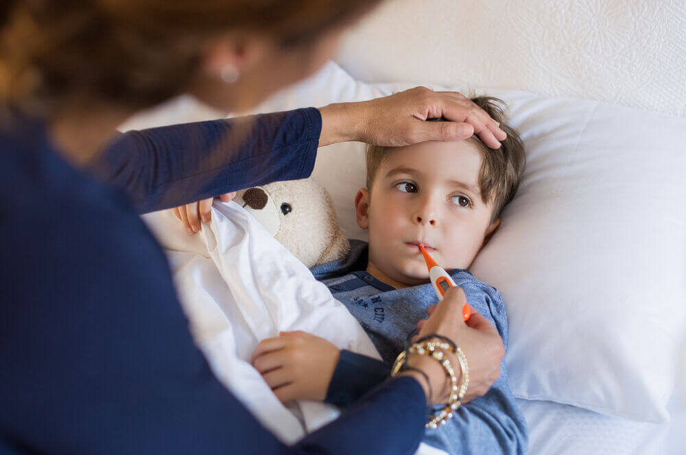 Child with thermometer at home